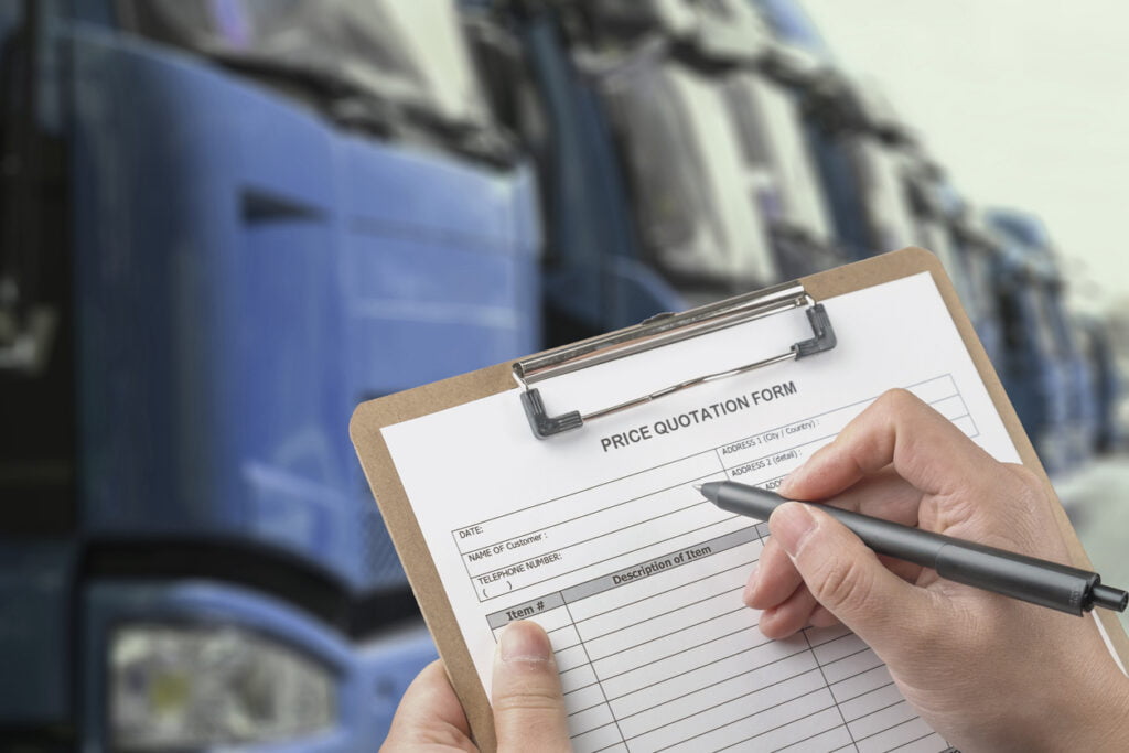 man holding auto transport quote form in front of a fleet of trucks