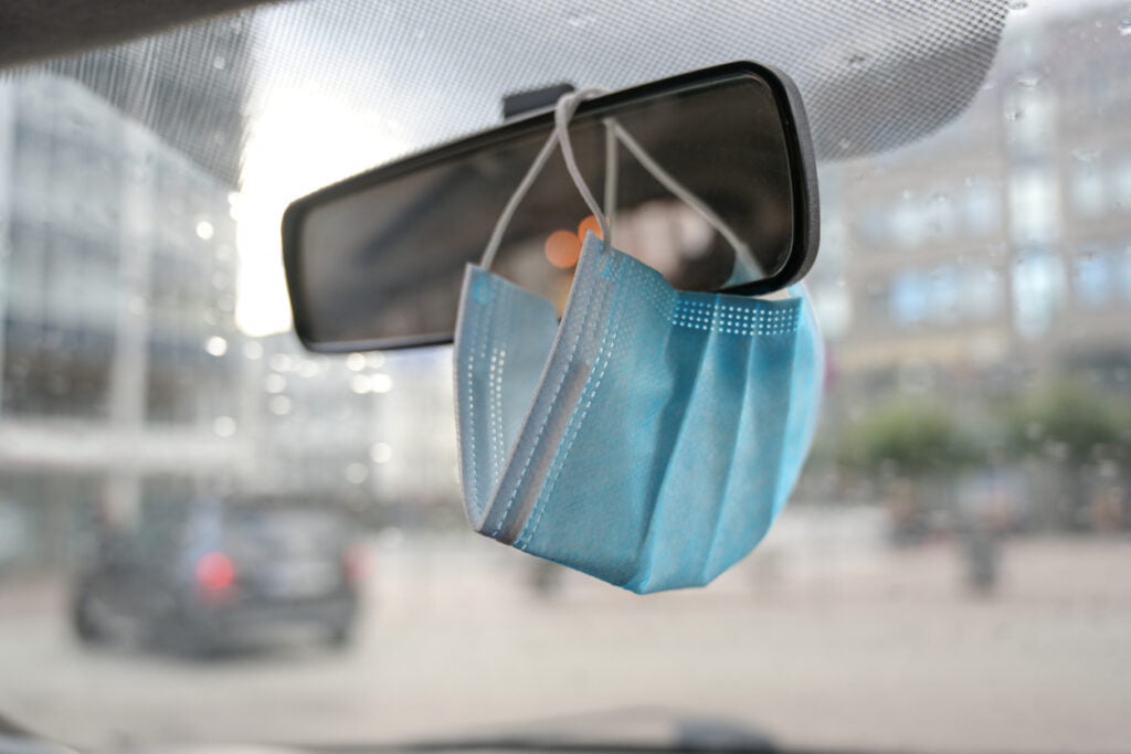moving vehicle with medical face mask on rearview mirror