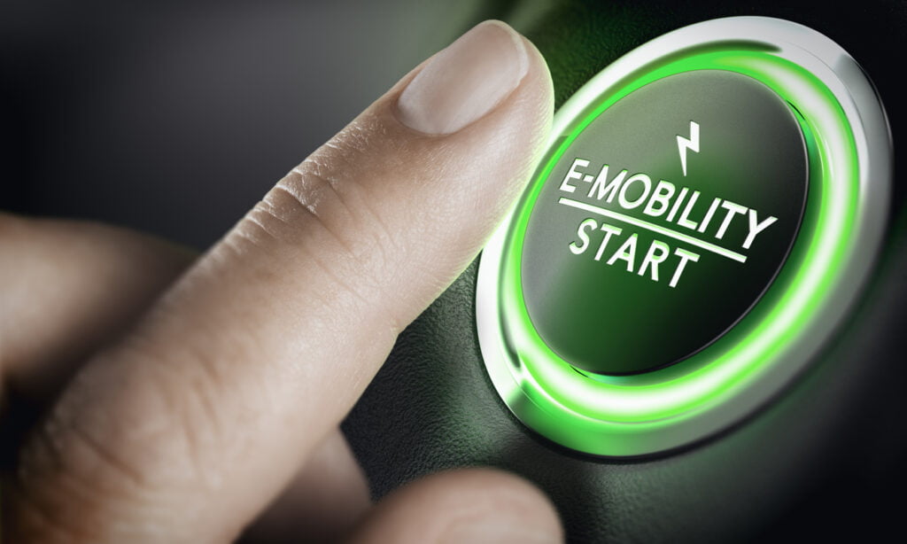 finger over a green-lit car button labeled “e-mobility start”