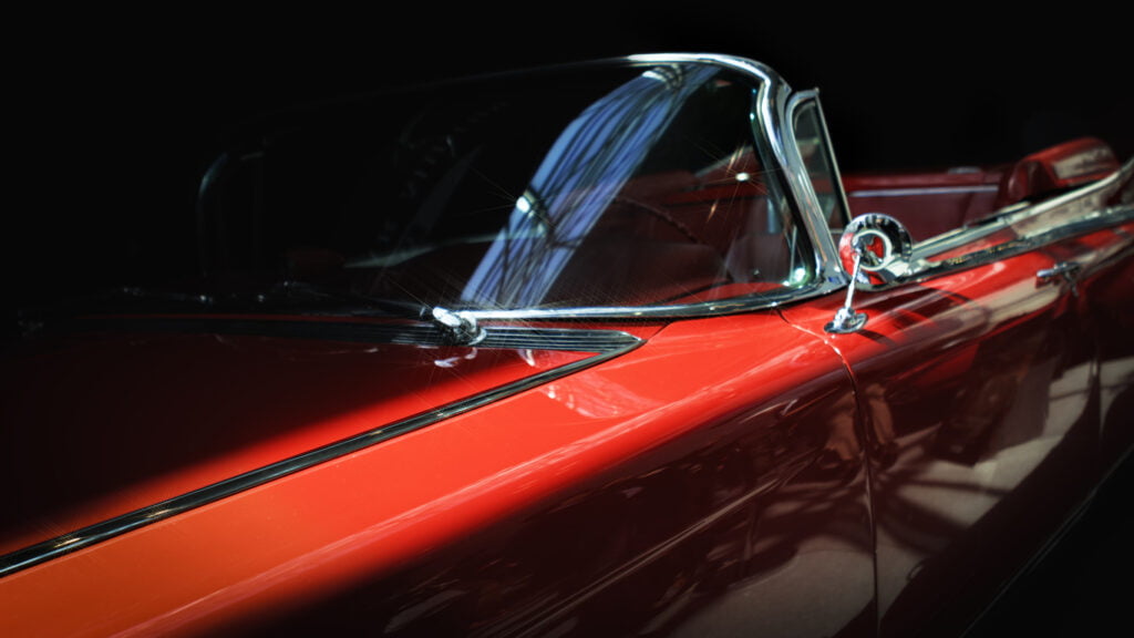 close-up of a stylish red classic car’s side profile against a black background