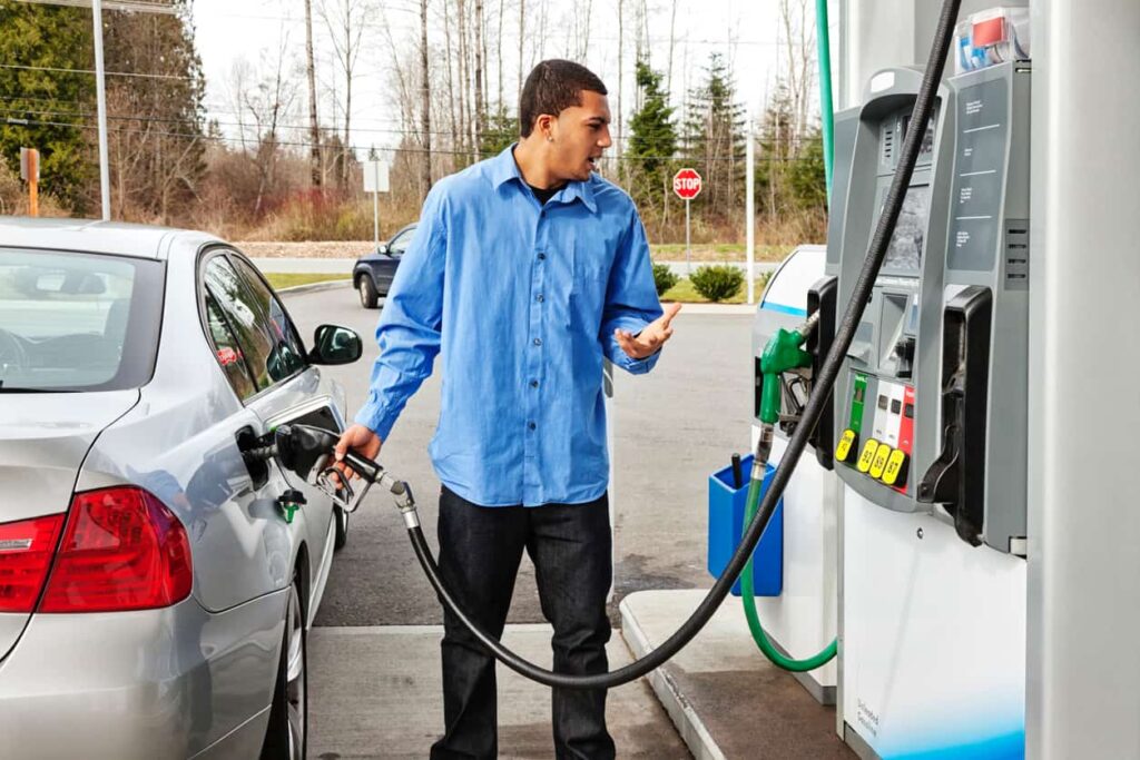 Man filling up his car while looking in disbelief at the gas prices