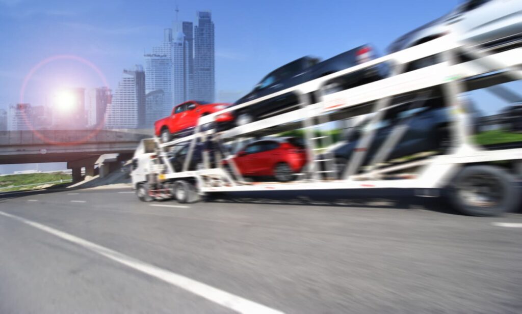 Auto carrier moving quickly down a freeway in a metropolitan area