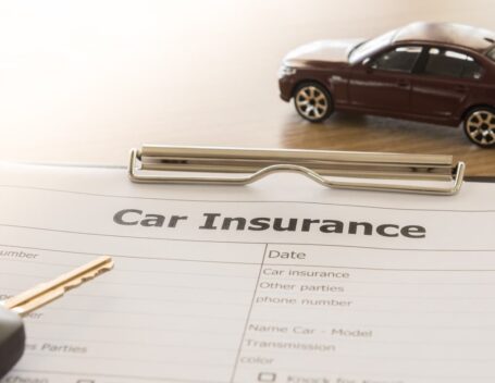 a vehicle, keys, and a car shipping insurance policy sitting on a desk.