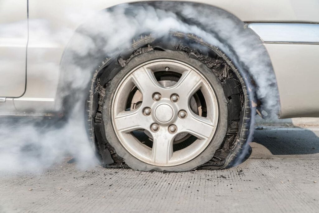 A close-up of a flat tire billowing smoke.