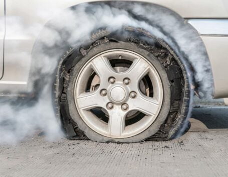 A close-up of a flat tire billowing smoke.