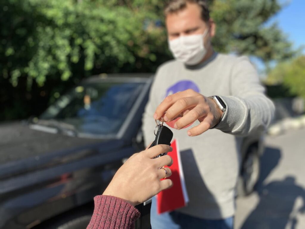 Man handing over car keys to a woman while completing a private car sale.