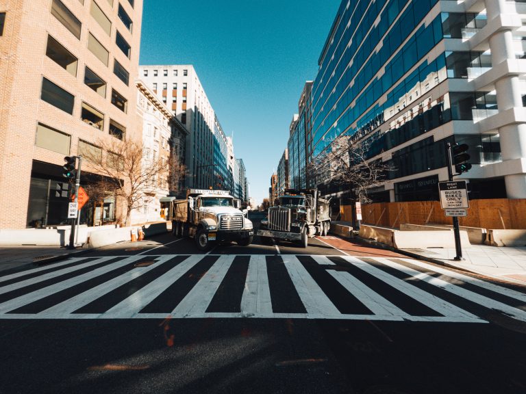 Trucks on road between modern house facades in town