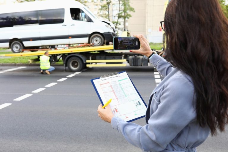 woman checking the process while van is loaded onto a flatbed for shipping