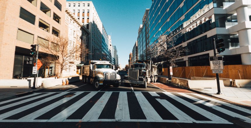 Trucks on road between modern house facades in town