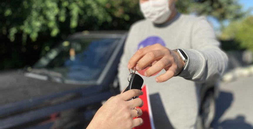 Man handing over car keys to a woman while completing a private car sale.