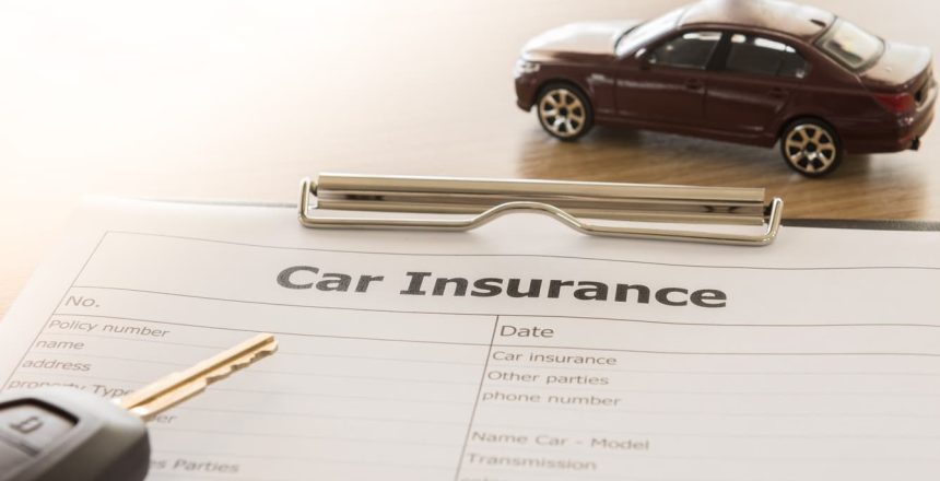 a vehicle, keys, and a car shipping insurance policy sitting on a desk.