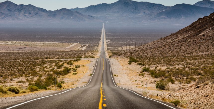 a long stretch of empty road reaching toward the mountainous horizon