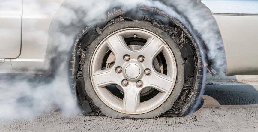 A close-up of a flat tire billowing smoke.