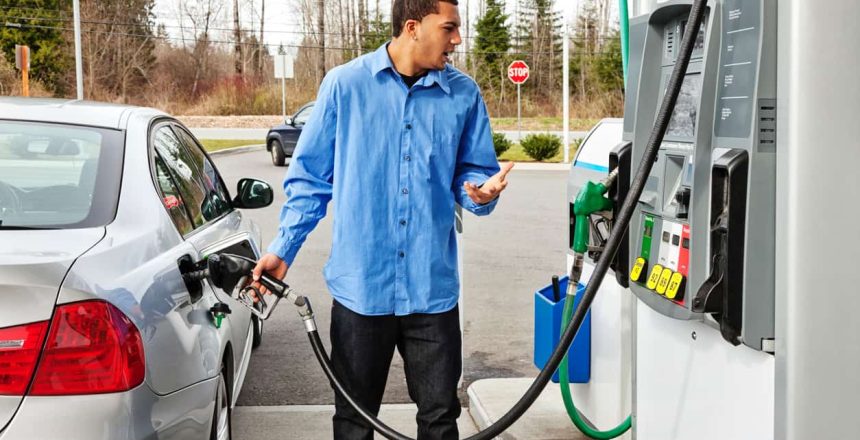 Man filling up his car while looking in disbelief at the gas prices