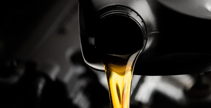 Motor oil pouring from a black container into an engine