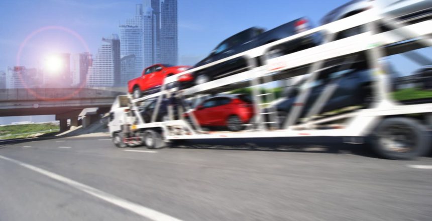 Auto carrier moving quickly down a freeway in a metropolitan area