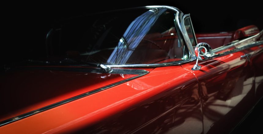 close-up of a stylish red classic car’s side profile against a black background