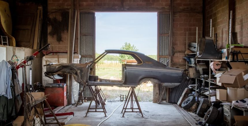 Car frame without doors, windows, or wheels mounted in a garage