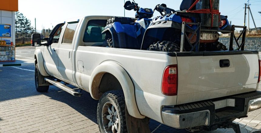 White pickup truck loaded with ATV near gas station